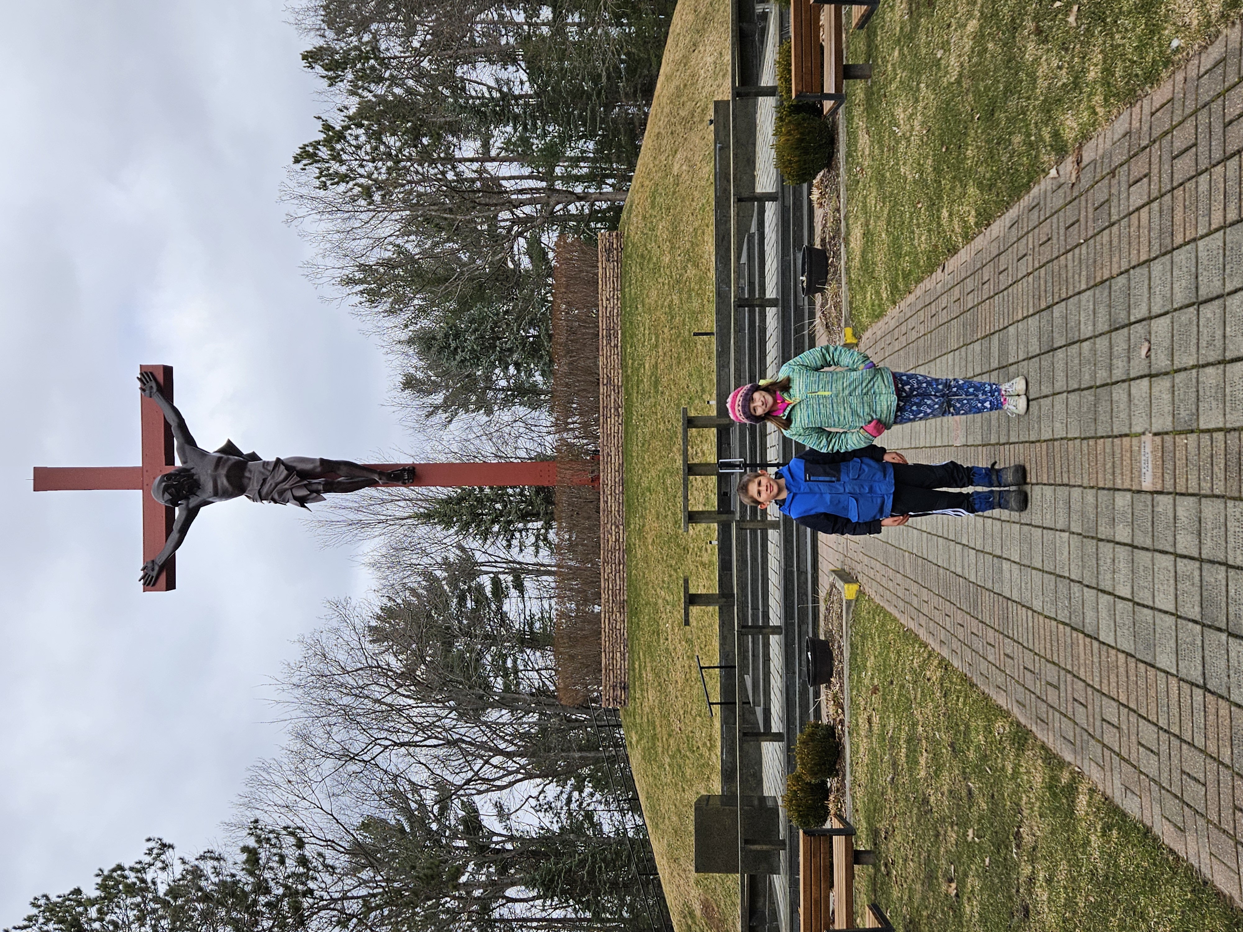 children in front of large cross