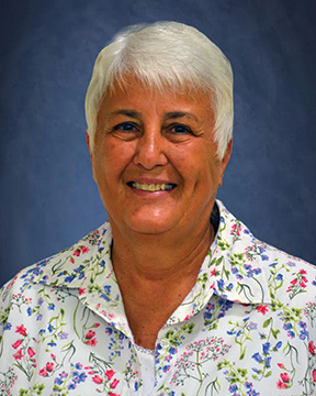 older woman with white hair and white floral shirt