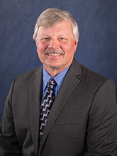 Gray haired man with mustache in suit and tie