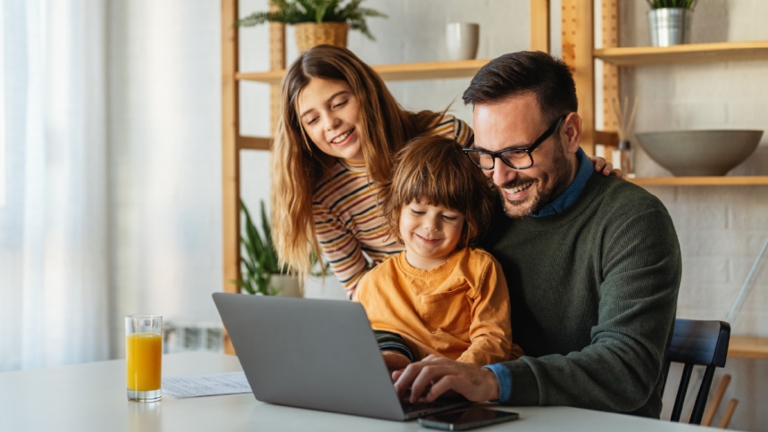 father and children look at computer